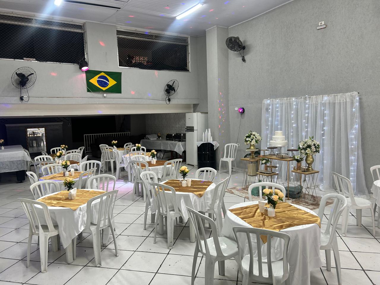 Salão montado com mesas e mesa do bolo